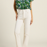 woman in green floral blouse and white denim on tan background 