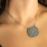 Necklace with a textured pendant worn by a person