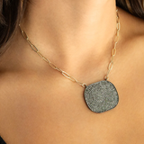 Necklace with a textured pendant worn by a person