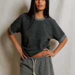 Woman wearing a gray oversized t-shirt and shorts against a plain background