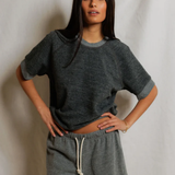 Woman wearing a gray oversized t-shirt and shorts against a plain background