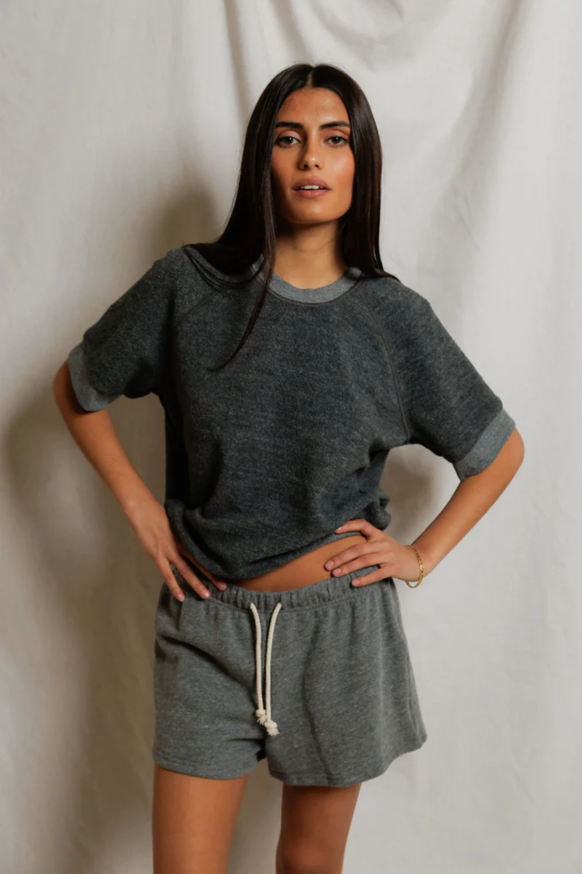 Woman wearing a gray oversized t-shirt and shorts against a plain background