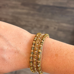 Beaded bracelet shown on someone's wrist featured on a blurred dark background.