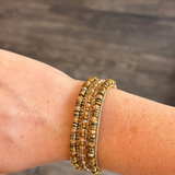 Beaded bracelet shown on someone's wrist featured on a blurred dark background.