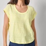 Woman wearing a yellow top and blue jeans against a plain background