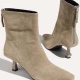 A pair of taupe suede ankle boots with pointed toes and kitten heels, shown from the side and back on a light beige background.