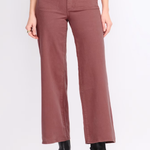 A model is wearing a pair of wide-leg cropped pants in a dusty rose or mauve color, styled with a cream cardigan, black top, and black ankle boots against a plain white studio background.