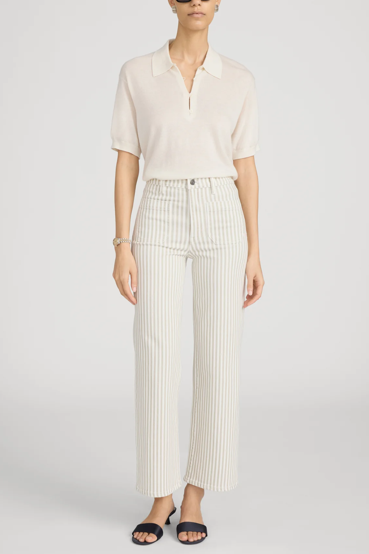woman in white top and stripe pants on white background 