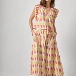 Woman wearing a sleeveless dress with a geometric pattern against a plain background