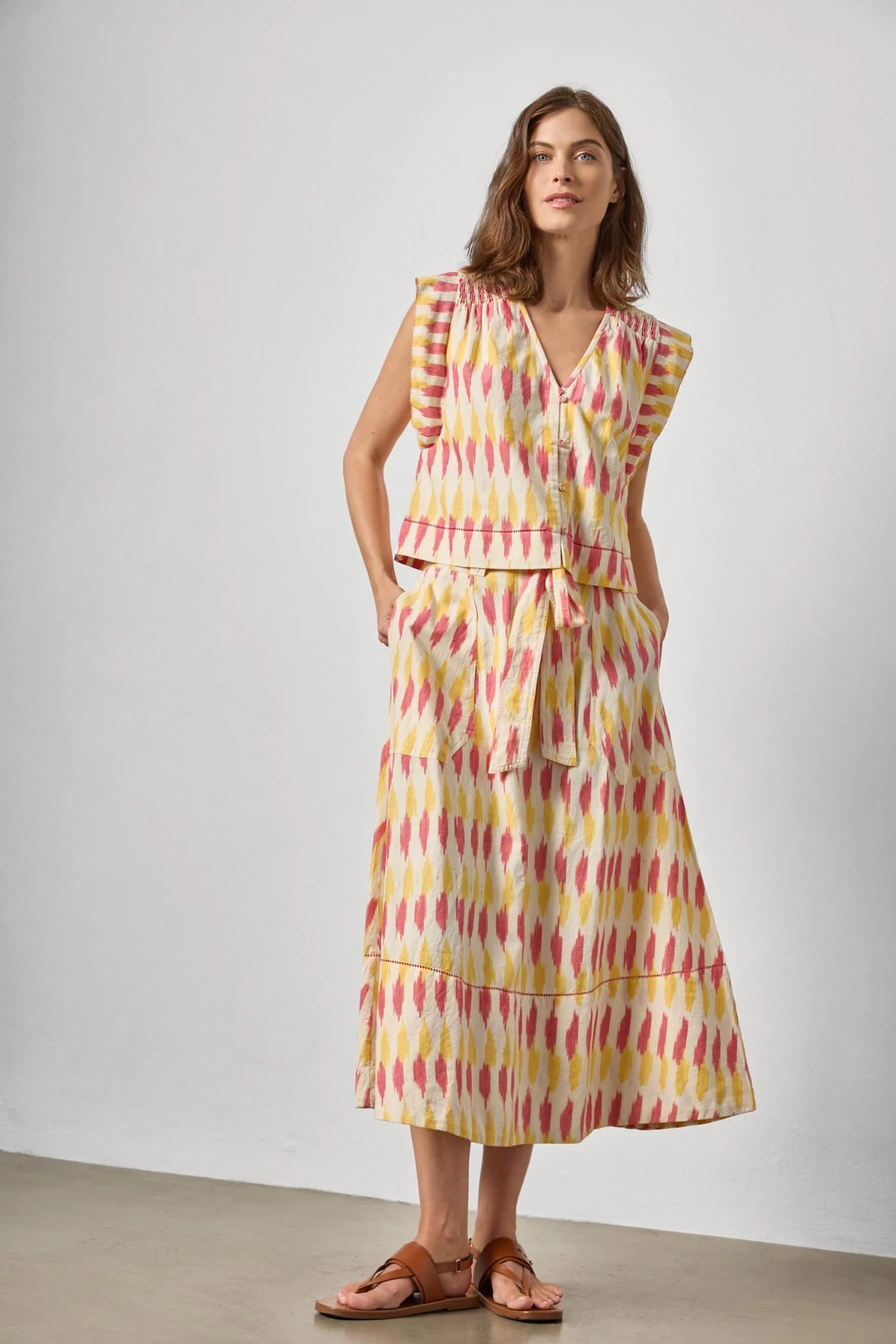 Woman wearing a sleeveless dress with a geometric pattern against a plain background