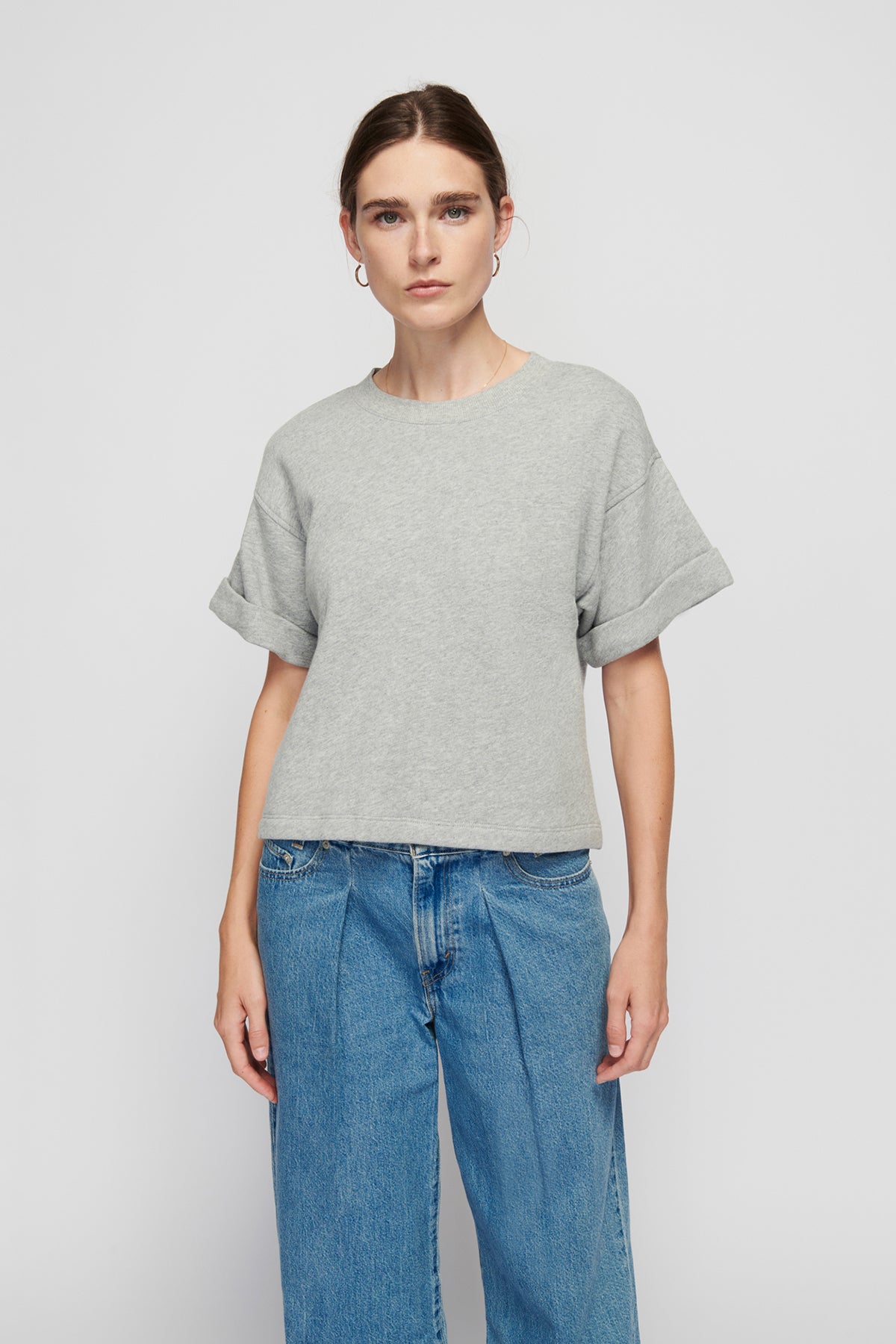 Person wearing a gray t-shirt and blue jeans on a white background