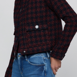 A cropped, long-sleeve plaid jacket in a dark red and black tweed-like fabric, worn by a model with blue jeans against a light gray background.