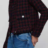A cropped, long-sleeve plaid jacket in a dark red and black tweed-like fabric, worn by a model with blue jeans against a light gray background.