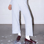 Woman wearing light grey knit pants with a straight leg silhouette, styled in soft studio lighting.