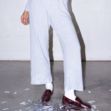 Woman wearing light grey knit pants with a straight leg silhouette, styled in soft studio lighting.