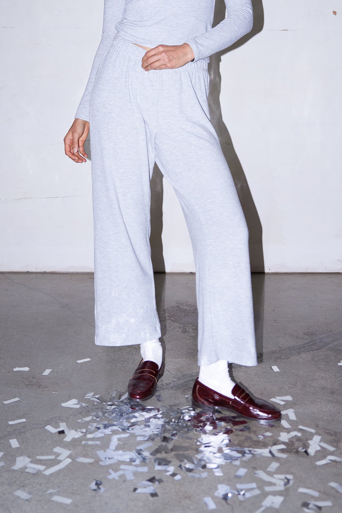 Woman wearing light grey knit pants with a straight leg silhouette, styled in soft studio lighting.