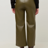 A person shown from the back wearing olive green wide-leg faux leather pants, a black long-sleeve top, and brown heeled ankle boots against a plain light background.