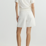 Person wearing a white top and shorts on a plain background