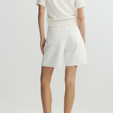 Person wearing a white top and shorts on a plain background