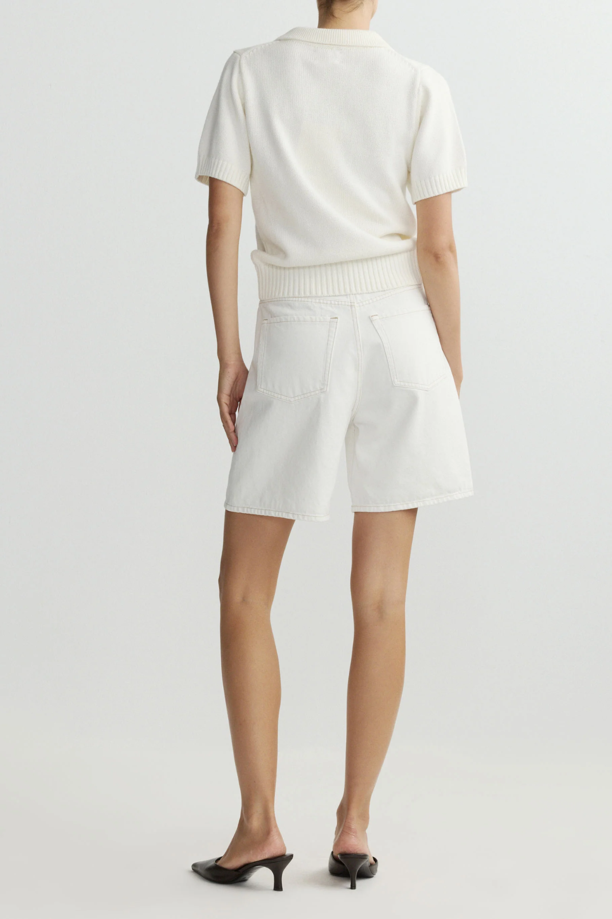 Person wearing a white top and shorts on a plain background