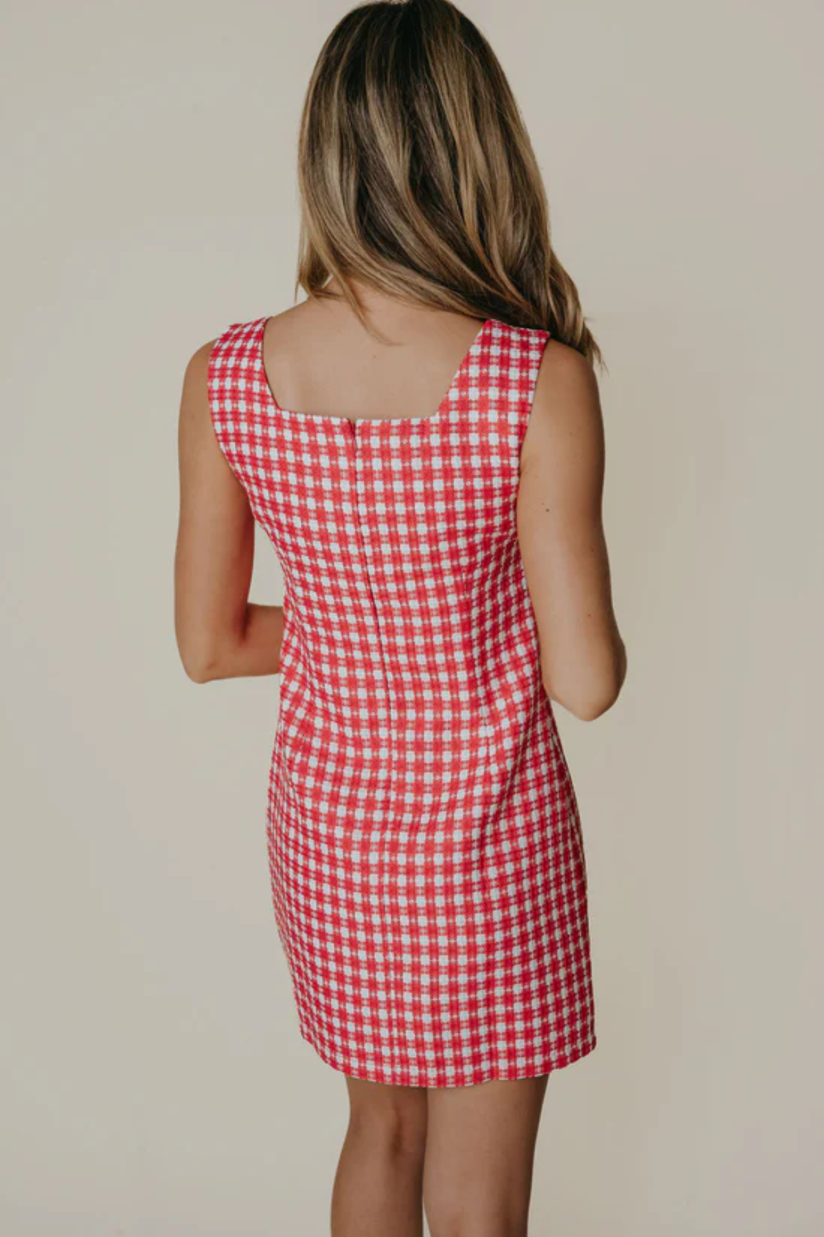 Red and white checkered dress worn by a person on a plain background