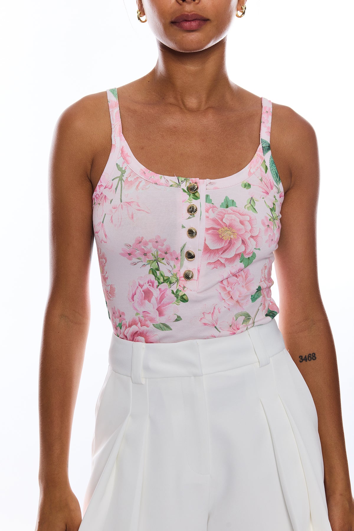 Woman wearing a floral tank top with pink flowers and white background