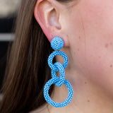 Close-up of a person wearing blue beaded earrings.