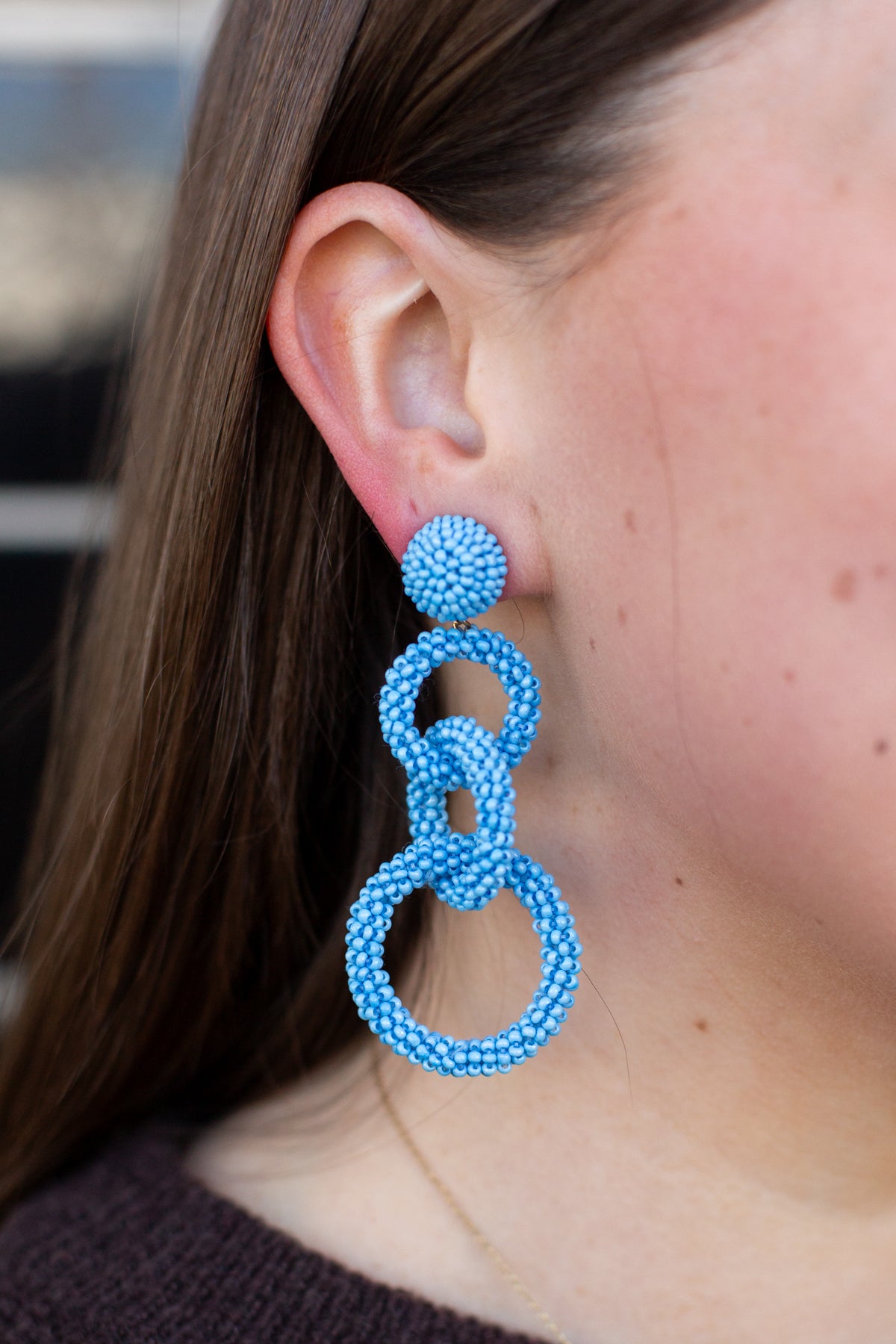Close-up of a person wearing blue beaded earrings.