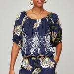 Woman wearing a navy floral top and pants on a plain background