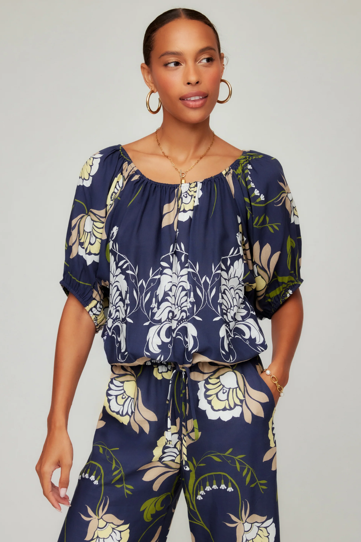 Woman wearing a navy floral top and pants on a plain background