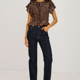 A model wearing a brown and black leopard-print ruffled short-sleeve top, dark wash blue jeans, and black heeled sandals, standing against a plain white studio background.