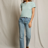Woman wearing a striped shirt and jeans standing against a plain background