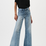 Woman wearing a black top and light blue wide-leg jeans on a white background