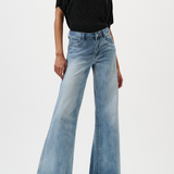 Woman wearing a black top and light blue wide-leg jeans on a white background