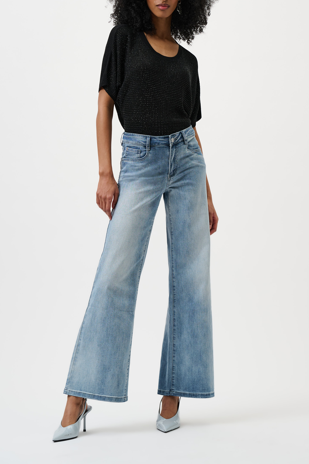 Woman wearing a black top and light blue wide-leg jeans on a white background