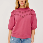 Woman wearing a pink blouse with lace details on a white background