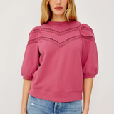 Woman wearing a pink blouse with lace details on a white background