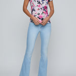 Woman wearing a floral top and light blue jeans on a gray background