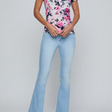 Woman wearing a floral top and light blue jeans on a gray background