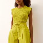 Woman wearing a bright yellow knit top and shorts set against a plain background