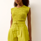 Woman wearing a bright yellow knit top and shorts set against a plain background