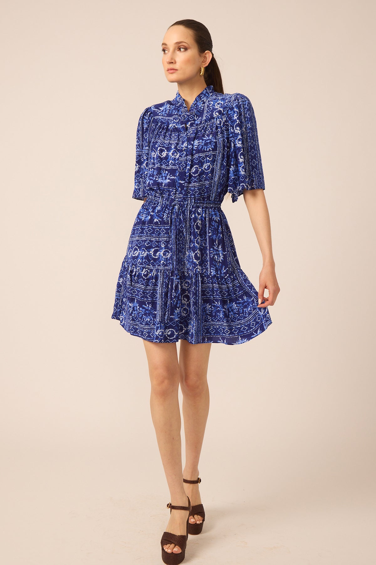 Woman wearing a blue patterned dress on a beige background