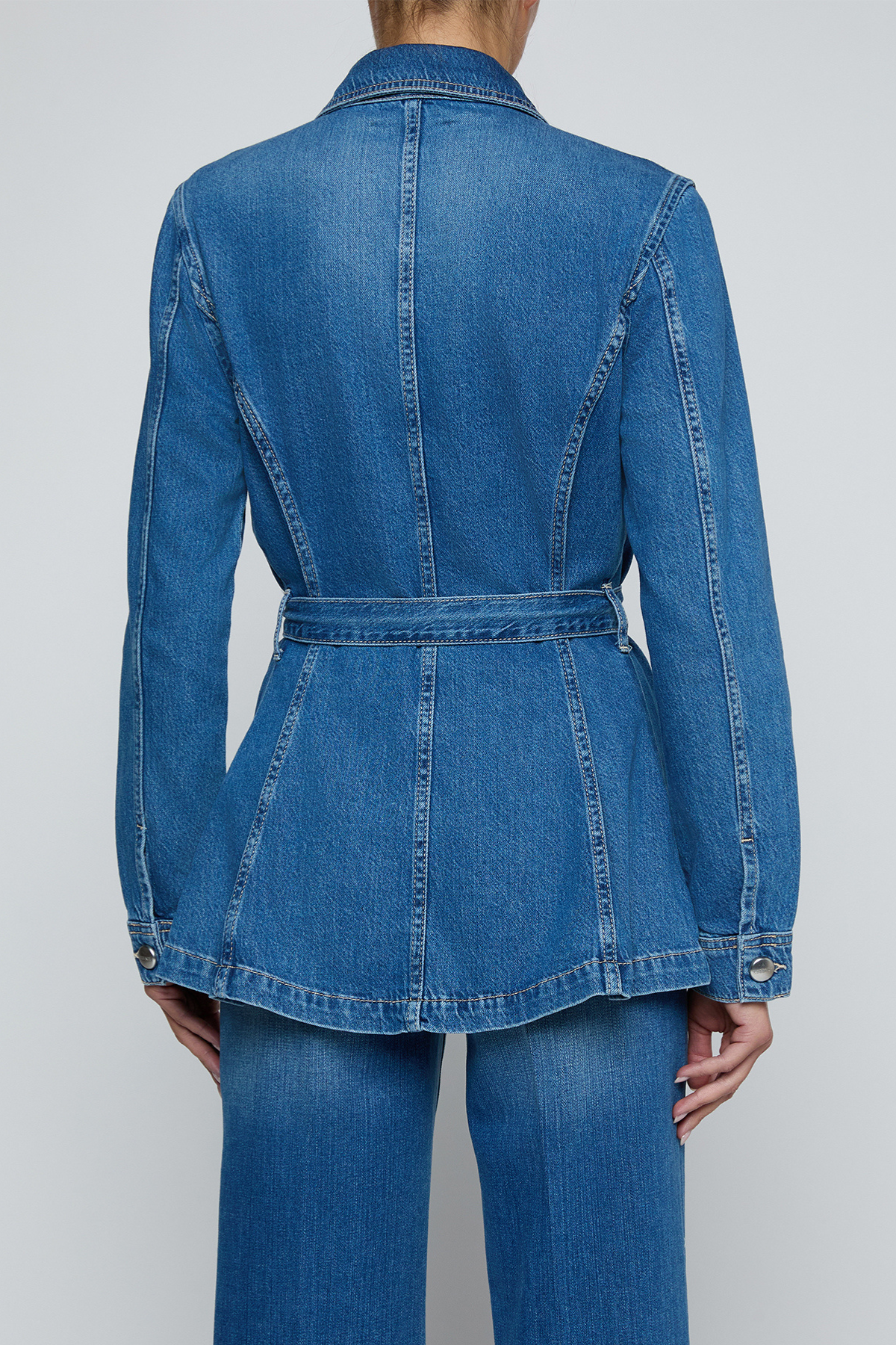 Model wearing a blue denim safari jacket with utility pockets and a button-front design.