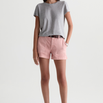 A woman modeling a light gray short-sleeve t-shirt and dusty pink shorts against a plain white studio background.