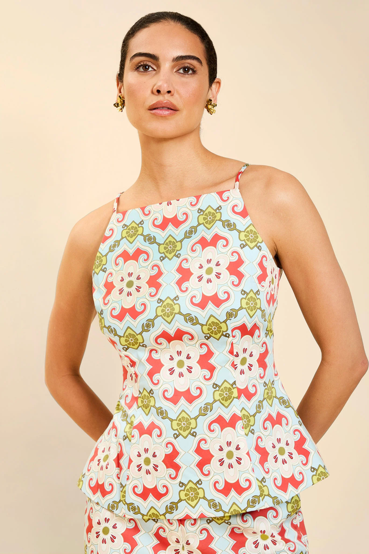 Woman wearing a colorful patterned top against a beige background