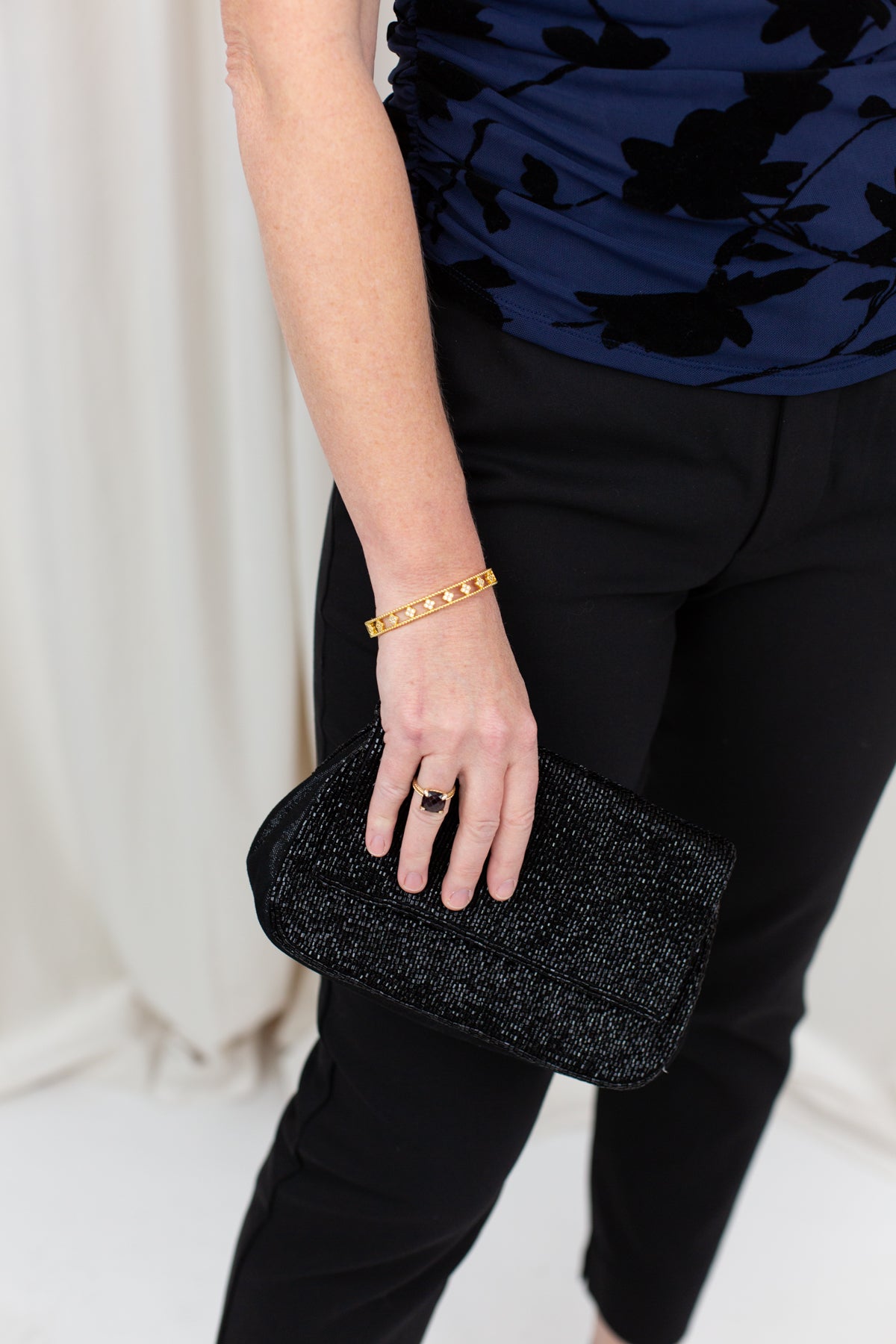 Gold clover bangle with pavé CZ detail, worn on wrist with a softly draped outfit.