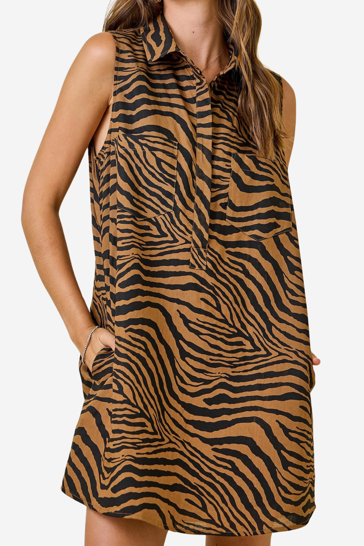 A sleeveless collared dress with a brown and black zebra print, featuring side pockets, shown on a model against a light gray background.