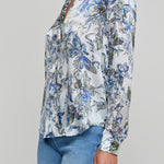 Woman wearing a floral blouse with long sleeves on a gray background