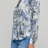 Woman wearing a floral blouse with long sleeves on a gray background