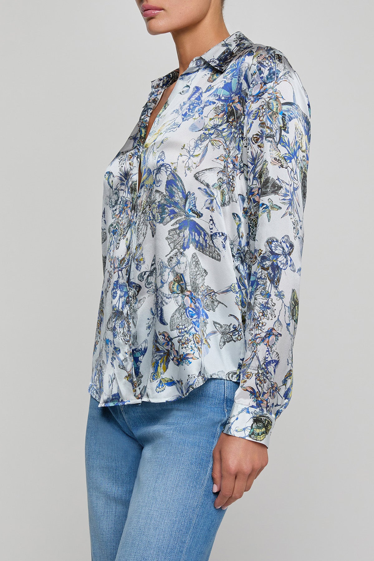 Woman wearing a floral blouse with long sleeves on a gray background